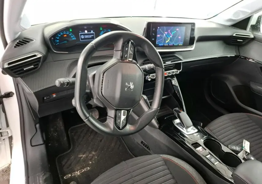 Vue intérieure côté conducteur du Peugeot 208 e-136 blanc, avec volant compact et écran tactile central.