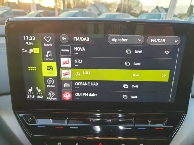 Écran tactile central du Volkswagen ID.4 noir Ebène, affichant la liste des radios FM/DAB en intérieur.