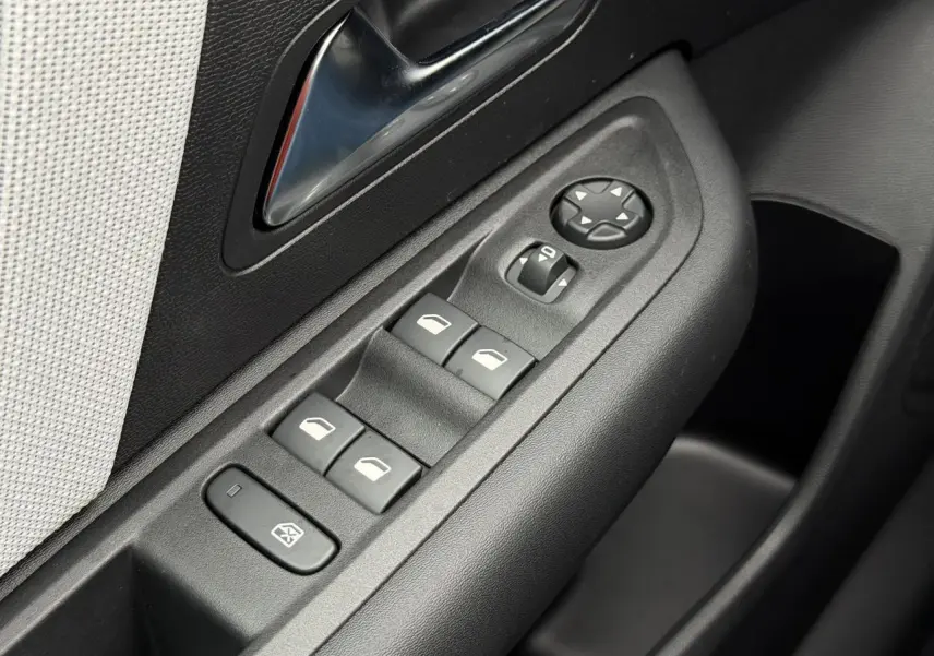 Gros plan sur les commandes de lève-vitres et rétroviseurs côté conducteur de la Citroën C4 gris Mercury, intérieur noir et tissu clair.