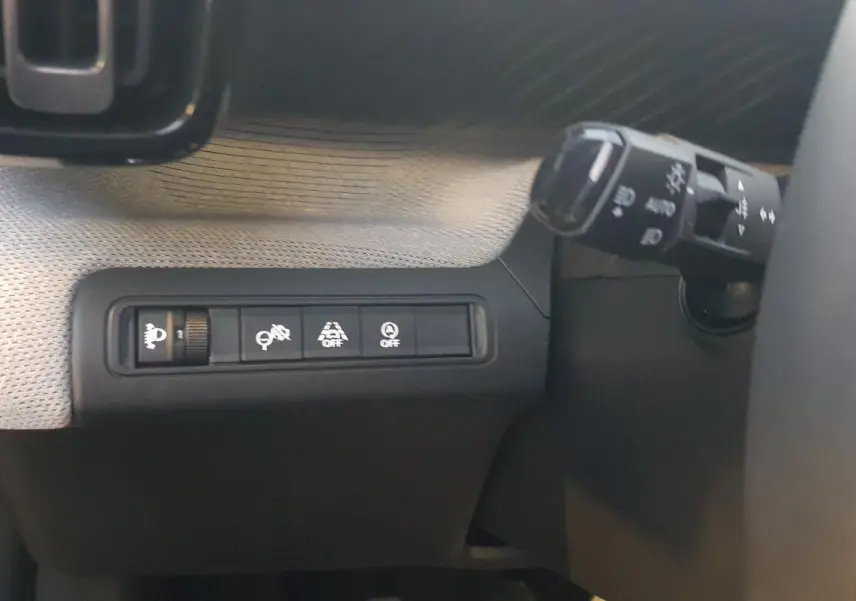 Détail des commandes d’assistance et éclairage côté gauche du volant dans l’habitacle d’une Citroën C3 noire.