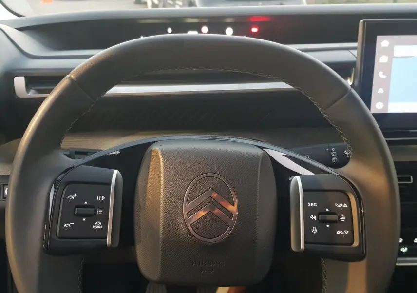 Vue rapprochée du volant noir de la Citroën C3 2025 avec commandes intégrées et tableau de bord numérique.