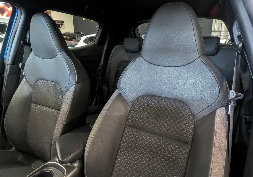 Gros plan sur les sièges avant en cuir noir du Nissan Juke Hybrid 2025, mettant en valeur leur design moderne et texturé.