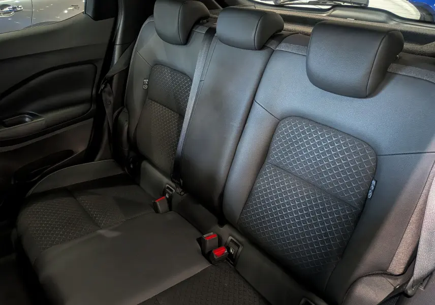 Vue rapprochée des sièges arrière noirs en cuir et tissu du Nissan Juke Hybrid 2025, avec appuie-têtes et ceintures visibles.