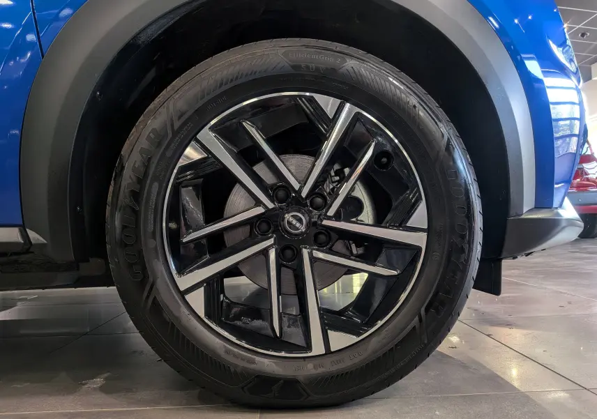 Gros plan sur la roue avant gauche du Nissan Juke Hybrid 2025 bleu magnétique, jante alliage noir et argentée.