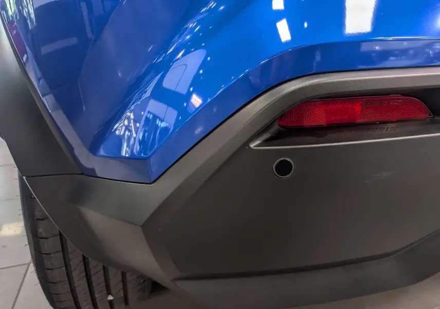 Gros plan sur l'angle arrière droit du Nissan Juke Hybrid 2025 en bleu magnétique avec feu rouge et pare-chocs noir mat.