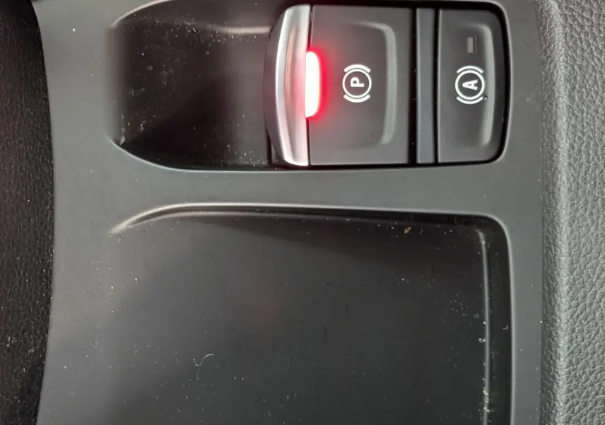 Gros plan sur les commandes de frein à main électronique et arrêt auto du moteur, intérieur noir de la Renault Clio hybride 2025.