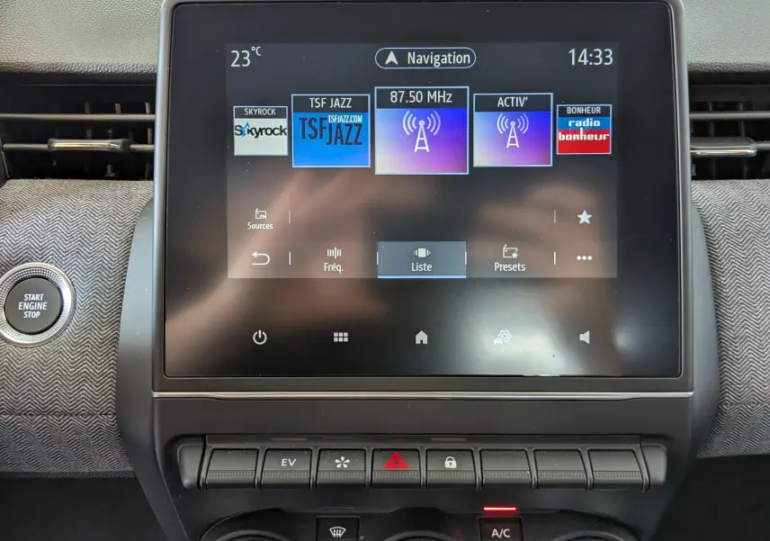 Écran tactile central de la Renault Clio V E-Tech gris schiste, affichant les stations radio avec bouton Start Engine à gauche.