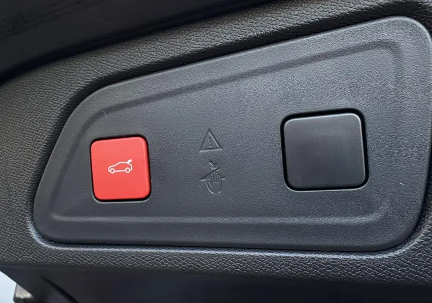 Boutons de commande du hayon électrique, dont un rouge avec icône de coffre, sur panneau intérieur noir du Citroën C5 Aircross Bleu Eclipse.
