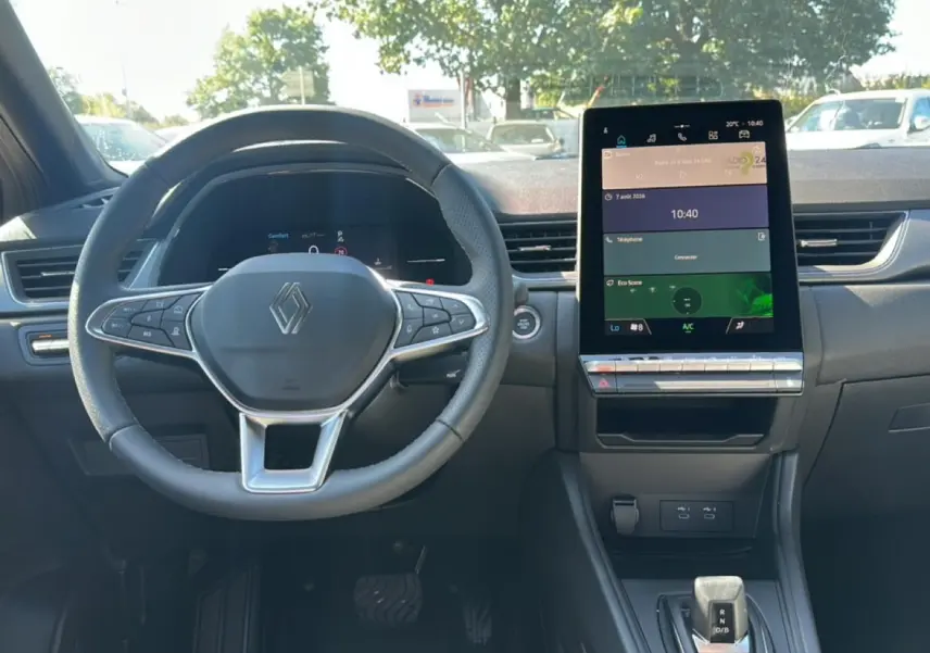 Vue intérieure frontale du tableau de bord et volant Renault Captur gris cassiopée avec écran tactile vertical et levier de boîte automatique.