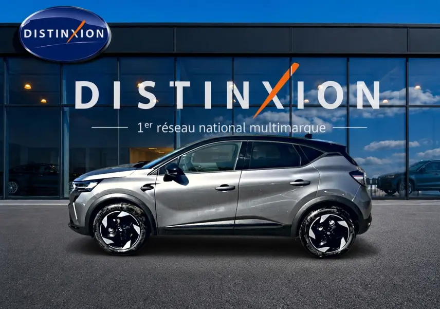 Profil droit d’un Renault Captur gris cassiopée 2026 avec jantes alu noires devant une vitrine Distinxion.