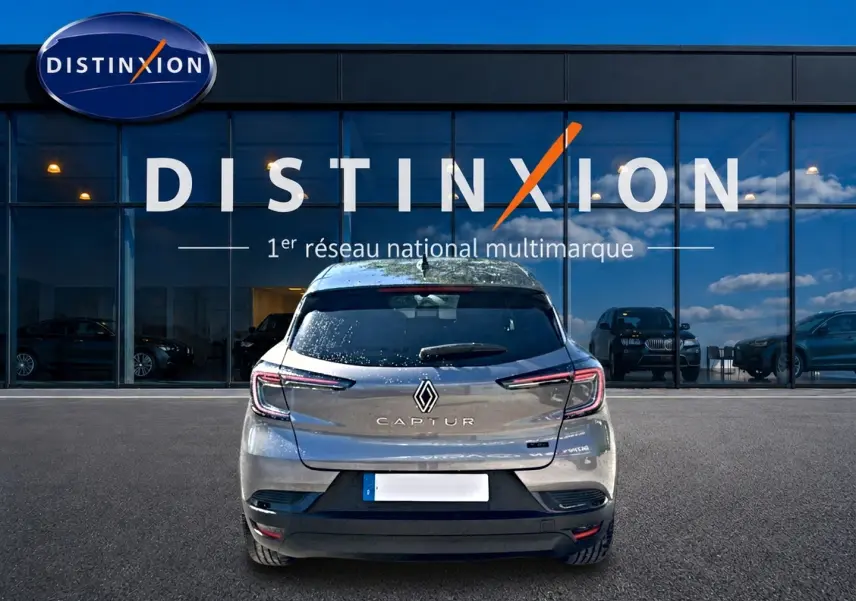 Vue arrière d'un Renault Captur gris cassiopée 2026, avec feux LED et logo distinctif sur fond de vitrine Distinxion.