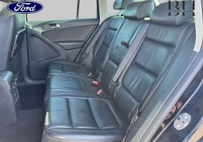Banquette arrière en cuir noir vue côté gauche d'un Volkswagen Tiguan beige, avec ceintures de sécurité visibles.