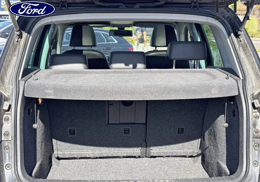 Coffre ouvert d’un Volkswagen Tiguan beige 2010, vue arrière montrant la banquette arrière et la plage arrière.