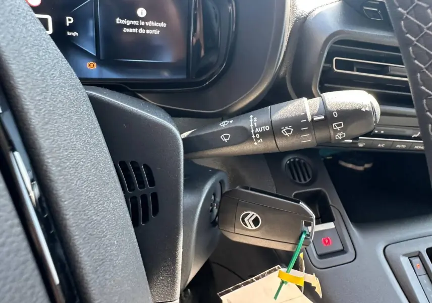 Gros plan sur le tableau de bord et clé de contact du Citroën Berlingo 2026, affichage digital et commandes noires.