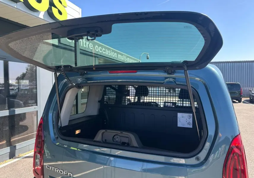 Vue arrière du Citroën Berlingo Kiama Blue avec hayon ouvert montrant l'espace de chargement et la grille de séparation.