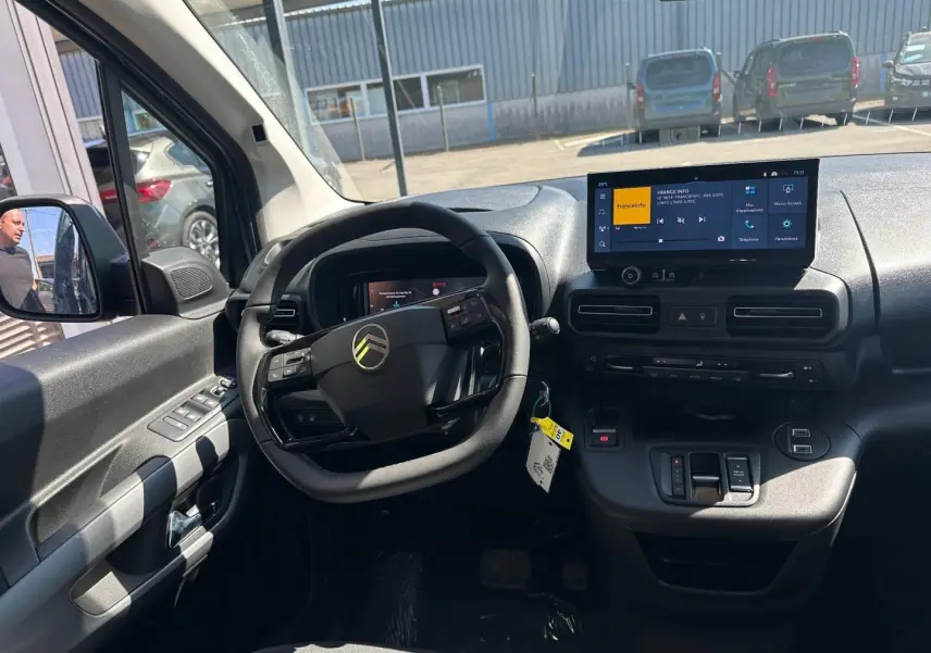 Intérieur du Citroën Berlingo 2026 vu côté conducteur, tableau de bord noir avec écran tactile et volant multifonction.