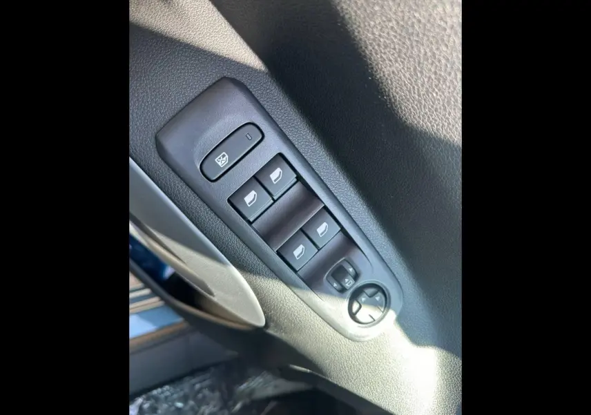 Gros plan sur les commandes des vitres électriques et rétroviseurs du côté conducteur d’un Citroën Berlingo Kiama Blue.