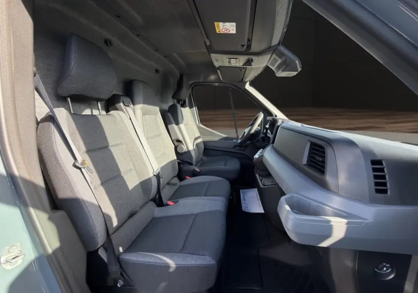 Vue intérieure côté conducteur du Renault Master 2026 avec sièges gris et tableau de bord sobre en plastique gris.