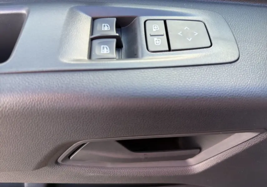 Gros plan sur les commandes de vitres et rétroviseurs électriques côté conducteur du Renault Master gris intérieur.