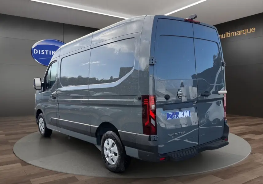 Vue 3/4 arrière droite d’un Renault Master gris foncé avec portes arrière fermées et logo visible sur fond showroom.