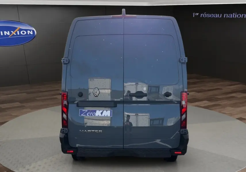 Vue arrière d’un Renault Master gris foncé avec portes battantes et feux arrière verticaux allumés.