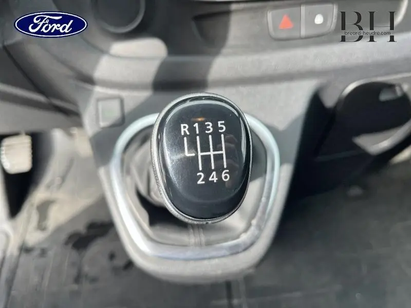 Le levier de vitesses manuel noir du Renault Trafic Fourgon blanc, vu en gros plan depuis l'intérieur.