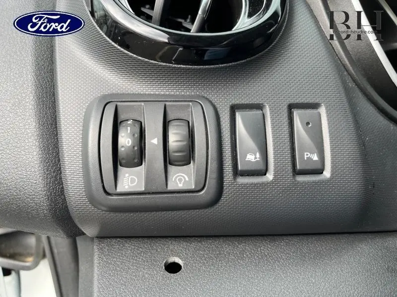 Gros plan sur les commandes de réglage des phares et aides à la conduite du Renault Trafic Fourgon blanc glacier 2020.