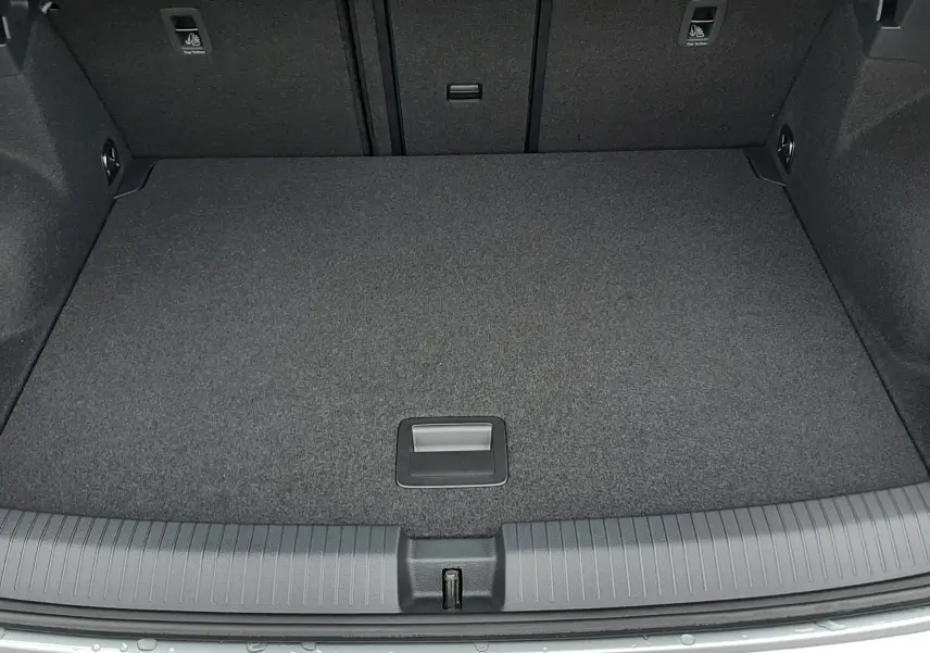 Vue plongeante sur le coffre spacieux et propre du Volkswagen T-Roc 1.5 TSI gris pyrite, avec tapis gris foncé.