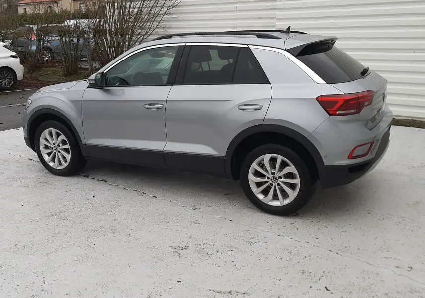 Vue côté gauche d'un Volkswagen T-Roc gris pyrite métal 2025, avec jantes alliage et toit ouvrant panoramique.