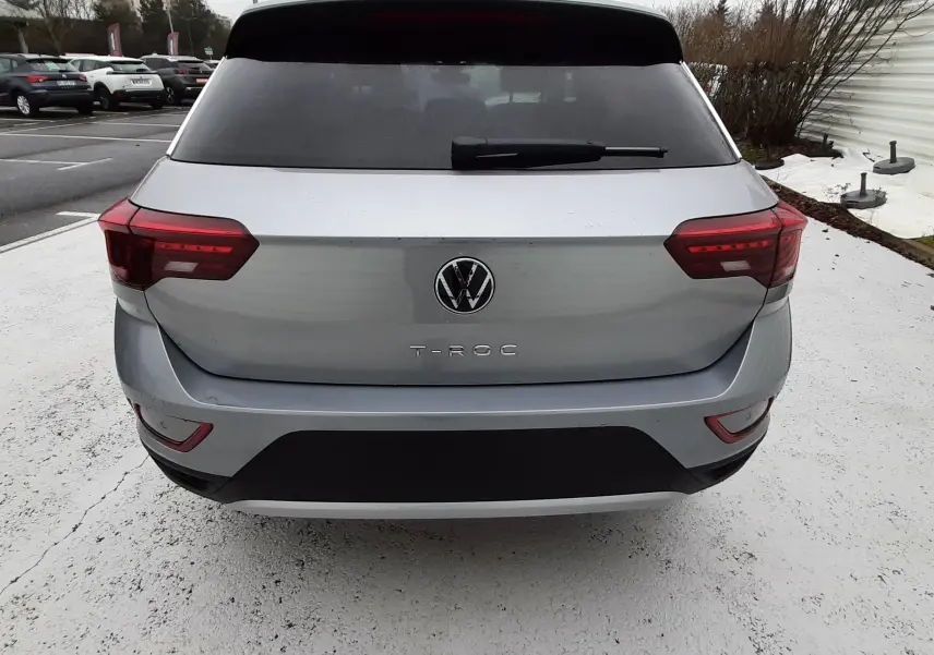 Vue arrière d'un Volkswagen T-Roc gris pyrite métal avec feux arrière LED et lunette arrière teintée.