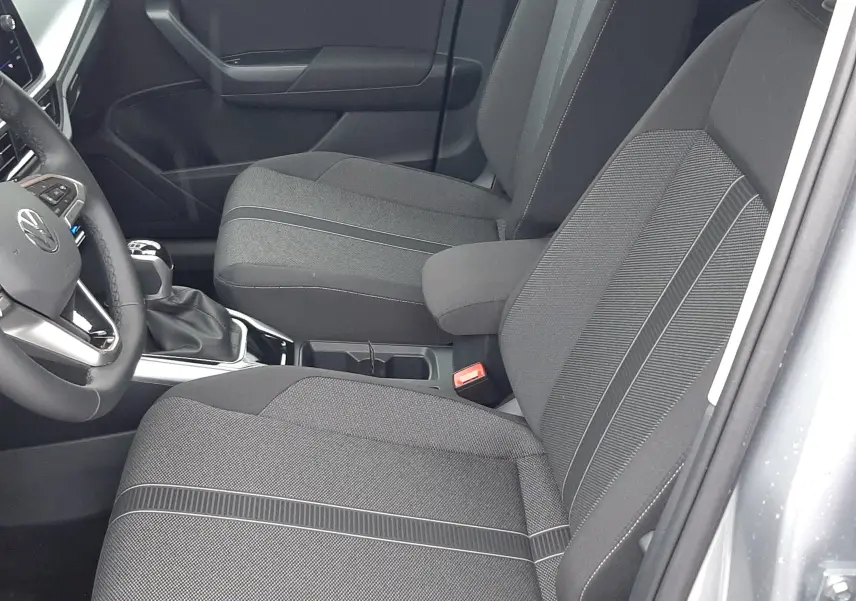 Vue intérieure côté droit du Volkswagen T-Roc 2025 gris pyrite, sièges tissu noir avec surpiqûres grises et console centrale.