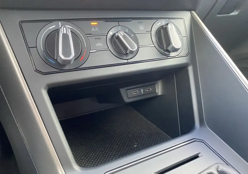 Gros plan sur la console centrale noire de la Volkswagen Polo 2020 avec commandes de climatisation et ports USB visibles.
