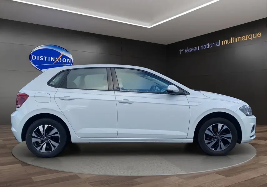Profil droit d’une Volkswagen Polo blanche Pure 5 portes, avec jantes alliage noires et grises, en showroom.