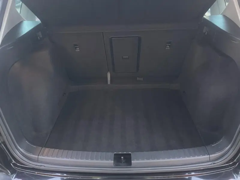 Vue intérieure du coffre ouvert du SEAT Ateca noir, montrant un espace de chargement propre et spacieux avec banquette arrière rabattable.