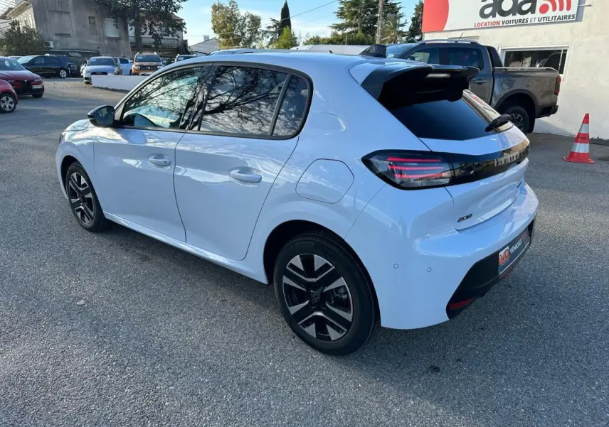 Peugeot 208 Hybrid blanc vue 3/4 arrière droit, jantes alliage noires et feux arrière LED distinctifs.