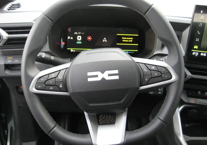 Vue rapprochée du volant noir avec logo DACIA stylisé et tableau de bord numérique du Dacia Bigster gris schiste 2026.