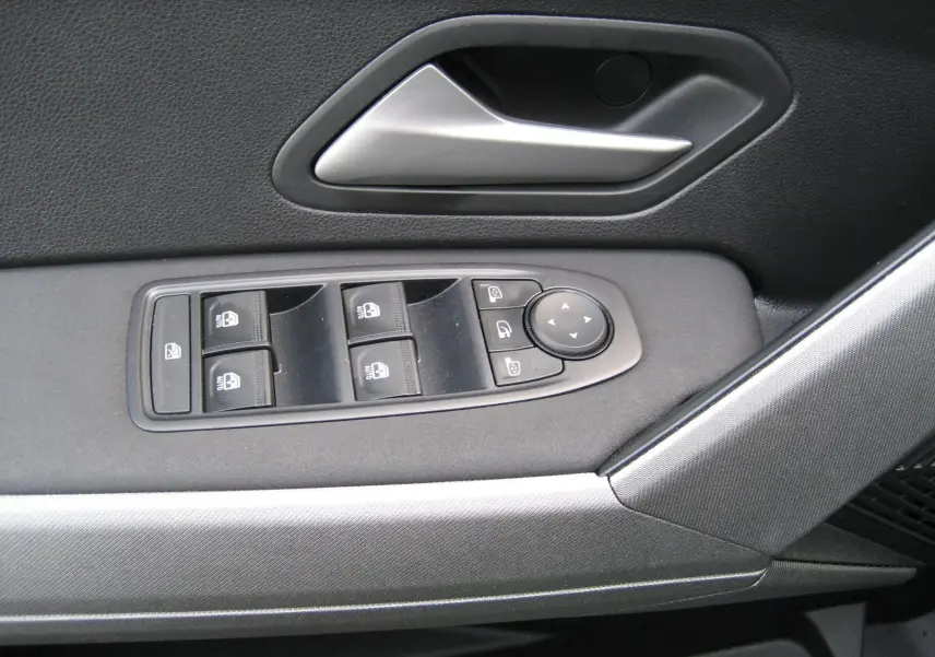 Gros plan sur la commande des vitres et la poignée intérieure côté gauche du Dacia Bigster gris schiste.