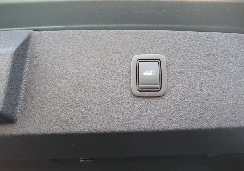 Bouton de commande d'ouverture du coffre sur le panneau intérieur d'un Dacia Bigster gris schiste.