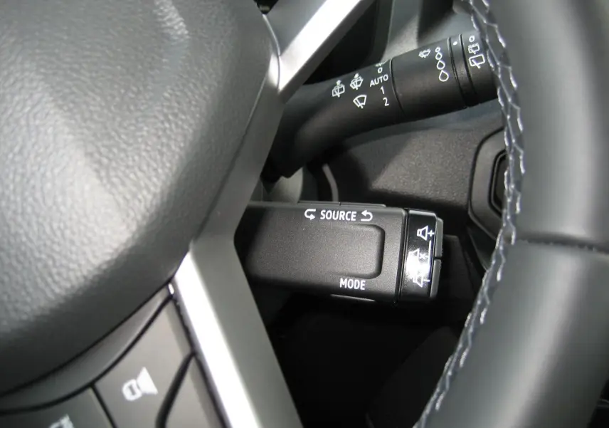 Gros plan sur la commande multimédia au volant du Dacia Bigster gris schiste, avec détails des boutons source et mode.