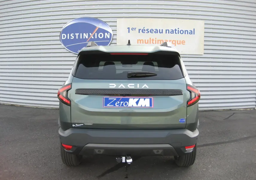 Vue arrière d'un Dacia Bigster gris schiste 2026 avec attelage et logo DACIA lumineux sur le hayon.