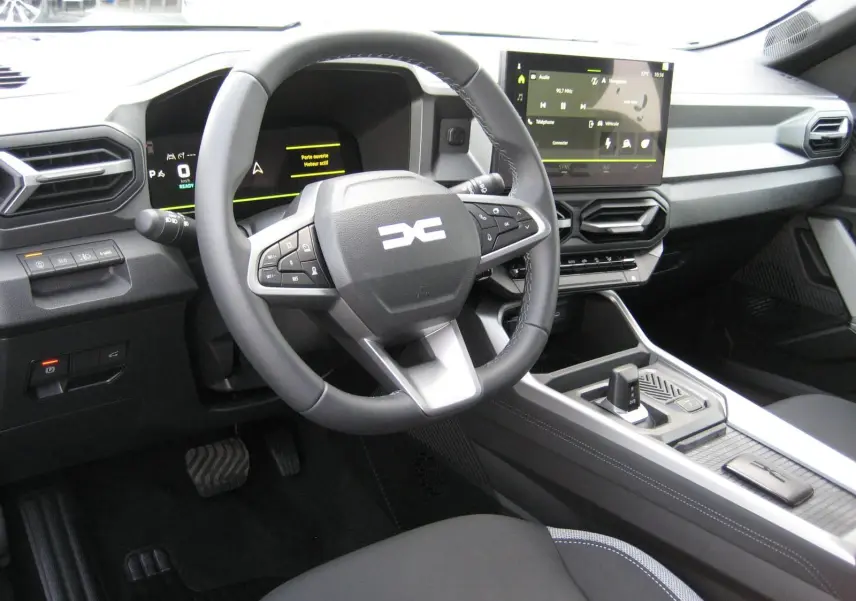 Vue intérieure du poste de conduite du Dacia Bigster 2026, avec volant multifonction et écran tactile central.
