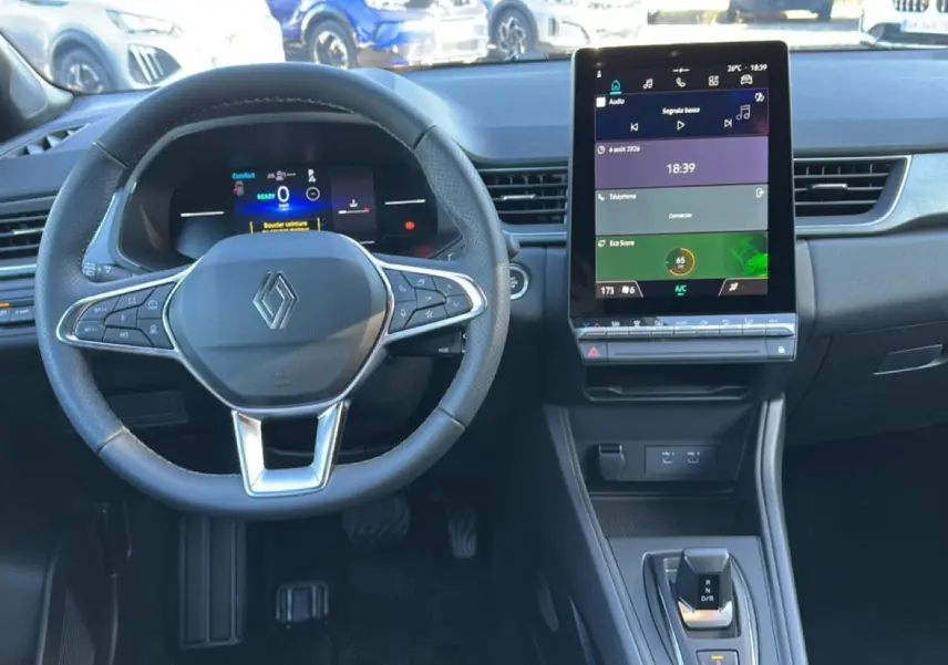 Vue intérieure du tableau de bord et volant du Renault Captur gris rafale, avec écran tactile vertical et commandes au volant.