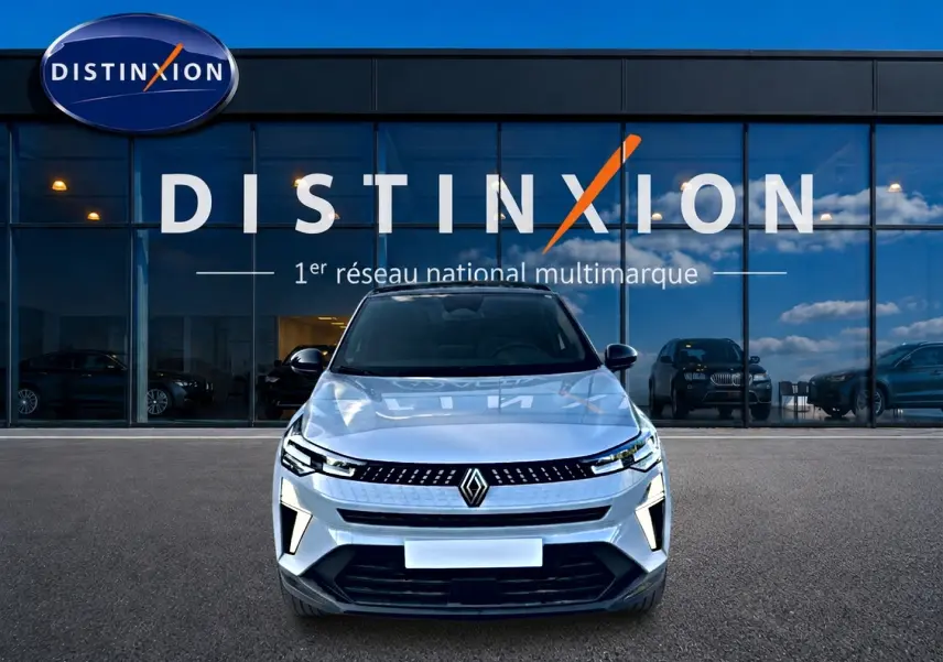 Vue frontale d'un Renault Captur gris rafale 2026 garé devant une vitrine avec logo Distinxion.