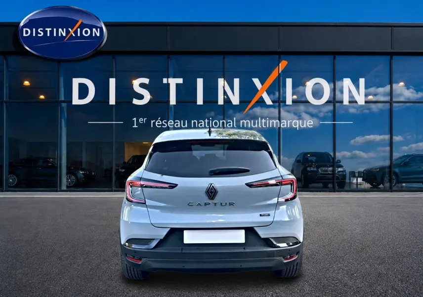 Vue arrière d'un Renault Captur gris rafale 2026 garé devant une vitrine avec logo Distinxion.