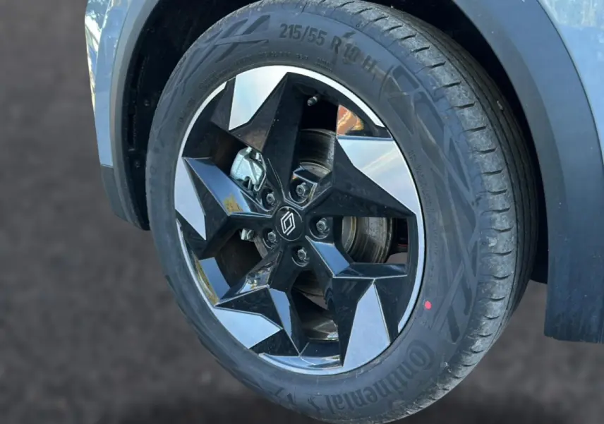 Gros plan sur la roue avant droite du Renault Captur gris rafale, mettant en valeur la jante alu noire et argentée au design géométrique.