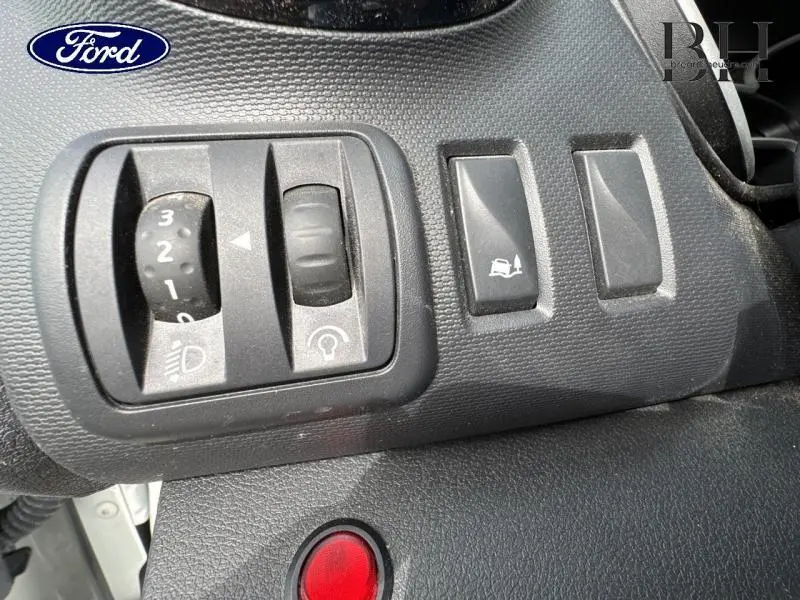 Gros plan sur les commandes de réglage des phares et de l'assistance à la conduite du tableau de bord du Renault Trafic blanc.
