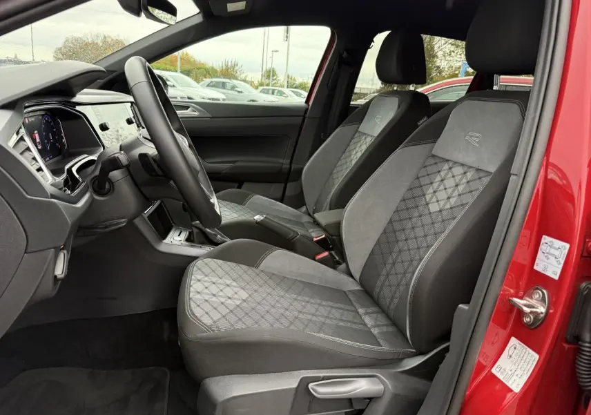 Vue intérieure côté gauche du Volkswagen Taigo Rouge Roi 2025, sièges Sport-Confort gris avec logo R brodé.