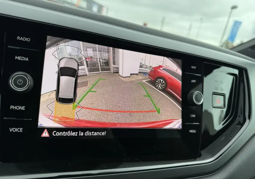 Vue de l'écran tactile intérieur montrant la caméra de recul du Volkswagen Taigo Rouge Roi avec aide au stationnement active.