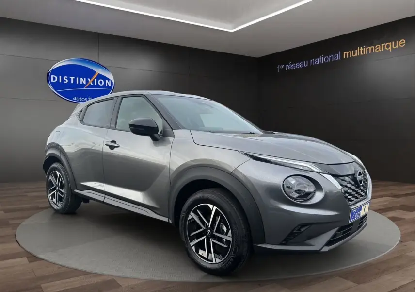 Nissan Juke 2025 gris squale en 3/4 avant droit, avec jantes noires et détails noirs contrastants.