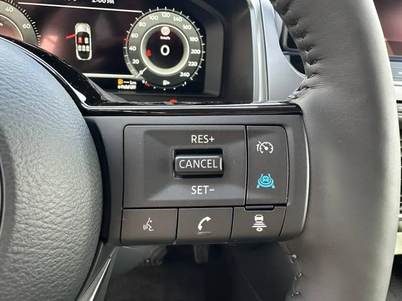 Gros plan sur les commandes au volant du Nissan Qashqai Hybrid e-POWER 2025, avec affichage digital en arrière-plan.
